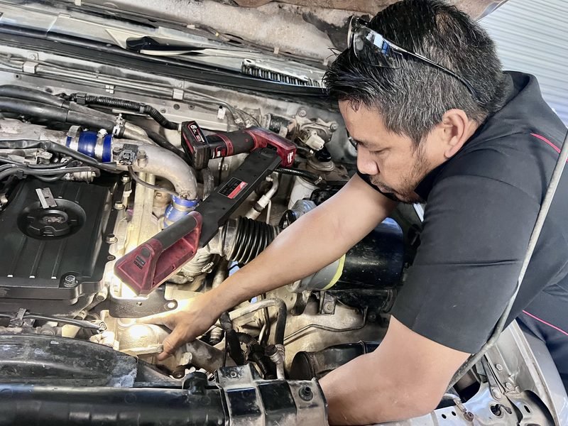 Doletin Mechanical's mechanic working in the engine bay of a car in the Berserker workshop